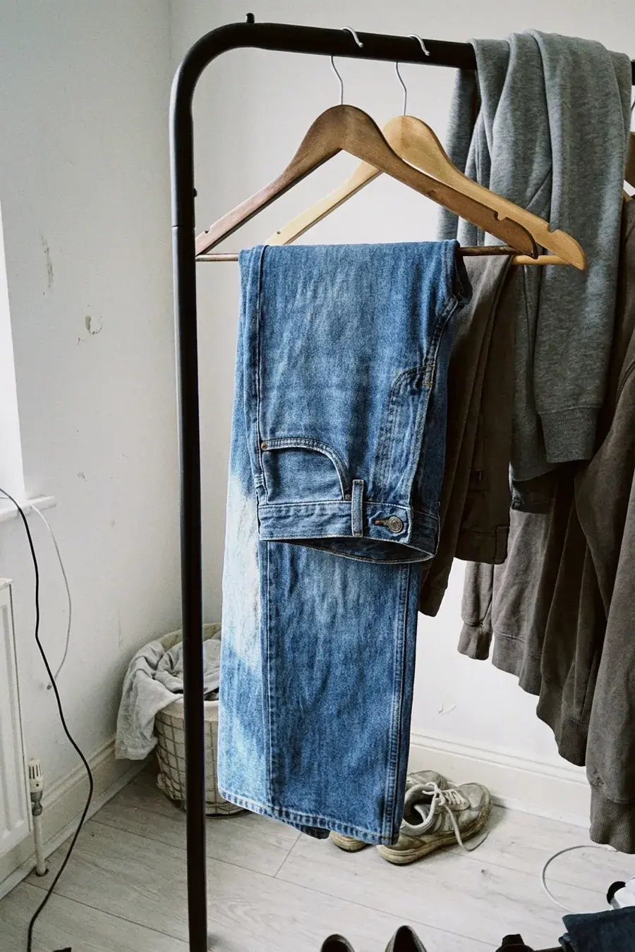Mellemblå jeans foldet over bøjle på tøjstativ